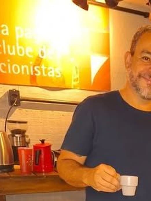 Retrato de Saulo Ribeiro, dramaturgo e editor da Cousa, camiseta azul-marinho, xícara na mão